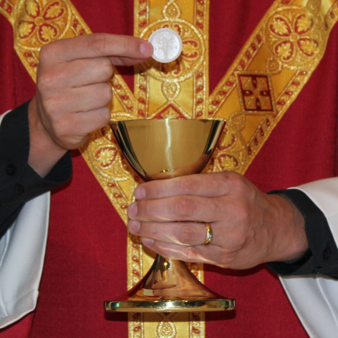 A priest holding a chalice with a coin in it.
