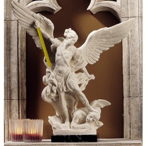 A statue of an angel with a ruler in front of a candle.
