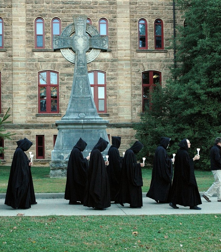 A group of monks in black robes walking in front of a building.