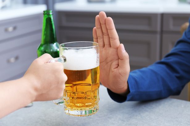 A man is holding a glass of beer and giving a thumbs up.