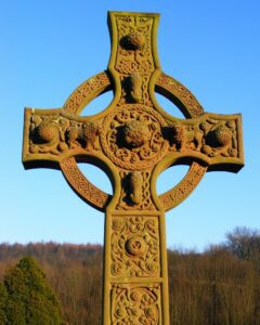 An ornate celtic cross in the middle of a field.