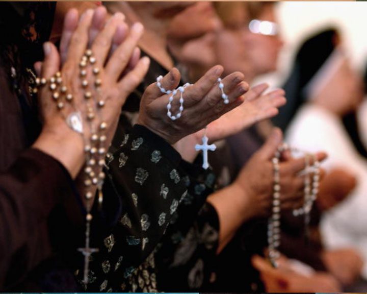 A group of people clapping their hands with rosaries.